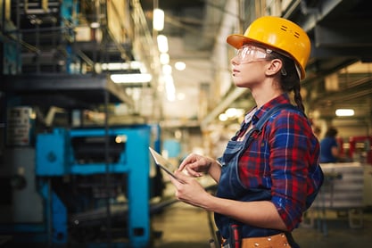 Female Factory Worker Using Tablet and Looking up at Shelves on Plant floor