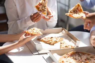 employees eating pizza together no faces