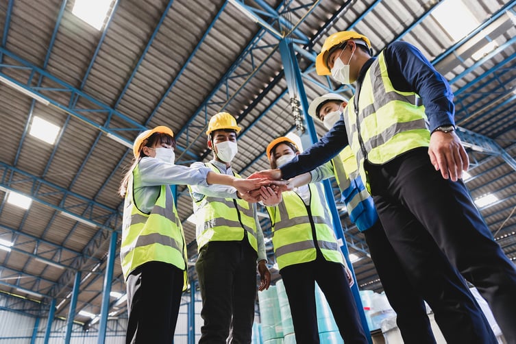 factory-workers-hands-in-yellow-safety-vests