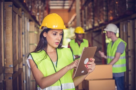 female-yellow-hard-hat-viewing-tablet-in-warehouse