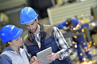 male-female-hardhats-looking-at-tablet