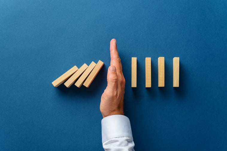 male-hand-stopping-dominos-falling-blue-background