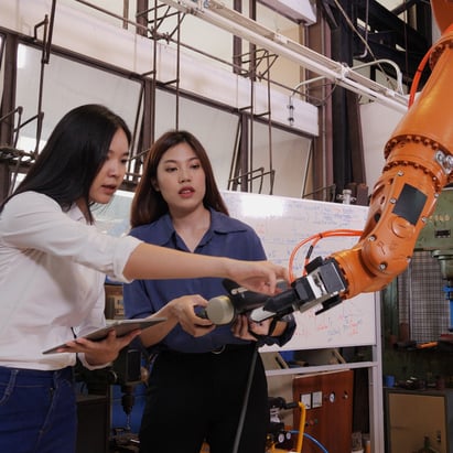 two-female-workers-robot-arm