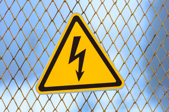 yellow-electrical-hazard-sign-on-fence